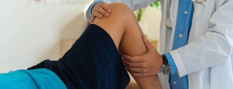 A healthcare professional uses medbridge digital tools to assess a patient's bent knee for injury or mobility issues.