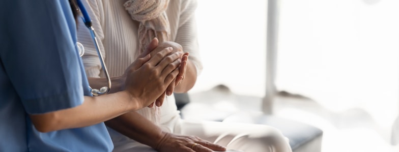A clinician in scrubs offers comfort to a seated person, illustrating medbridge digital healthcare support.