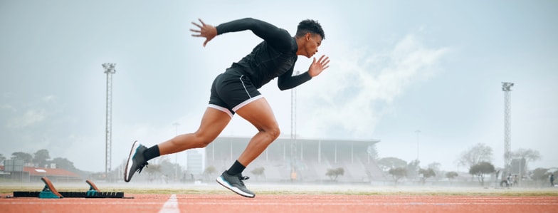A sprinter launches from starting blocks on an outdoor track, symbolizing digital healthcare progress with medbridge.