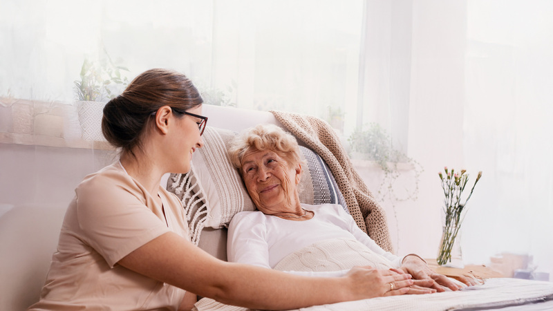 A caregiver and an elderly person in bed share a warm moment with medbridge technology enhancing their connection.