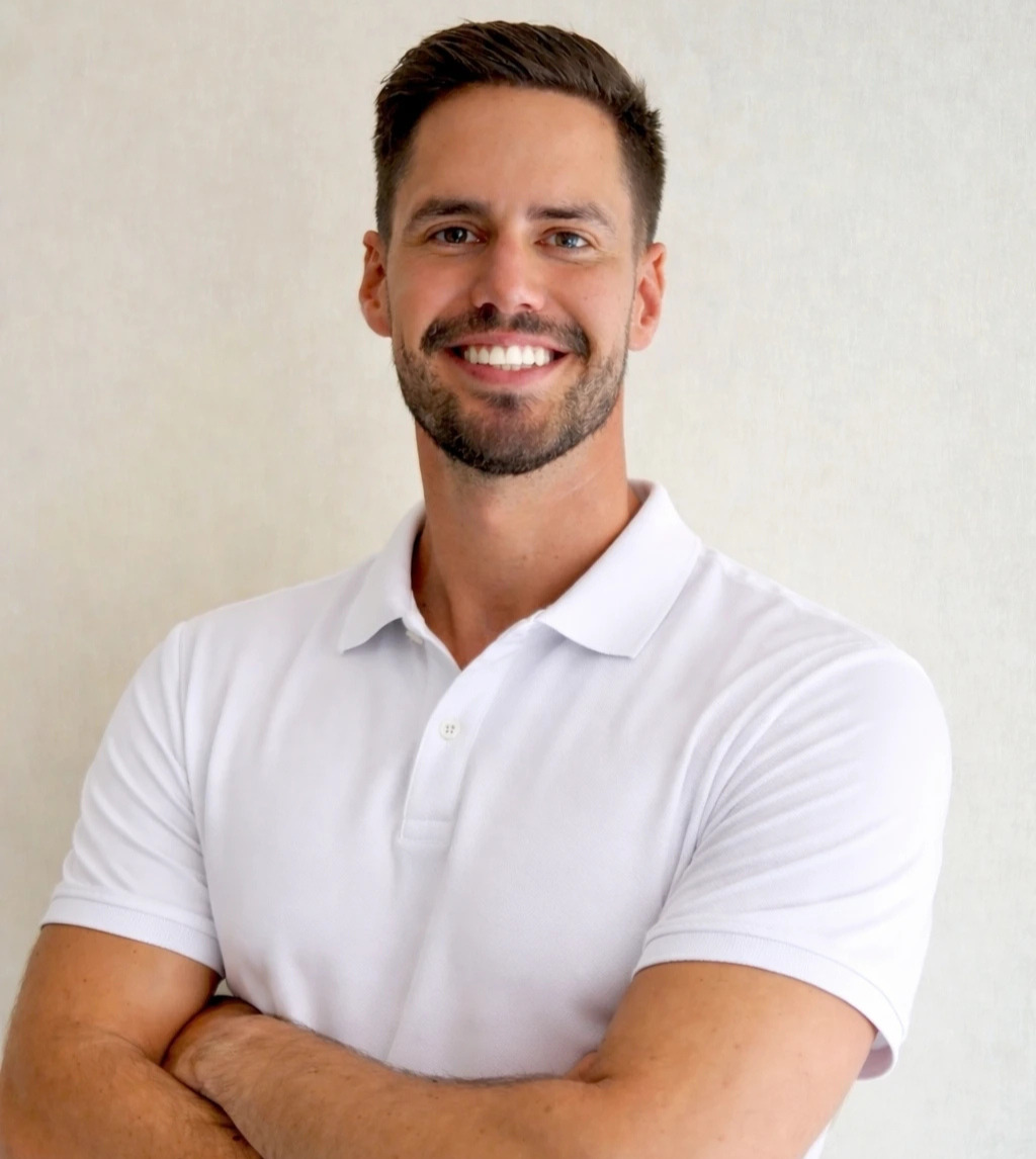 A smiling man with short brown hair and a beard stands with arms crossed in front of a plain background, representing medbridge digital healthcare.