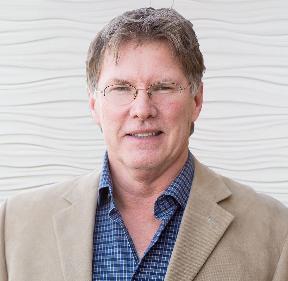 A man in glasses and a beige jacket embodies digital healthcare's future standing against a wavy wall, representing medbridge.
