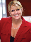 A smiling blonde woman in a red blazer engages with advanced patient care software during healthcare training at medbridge.