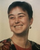 A smiling person with short dark hair in a floral top and earrings represents the positivity found in healthcare education, as medbridge nurtures patient care skills.