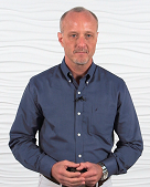 A man in a blue shirt holds a digital healthcare device against a textured white backdrop.