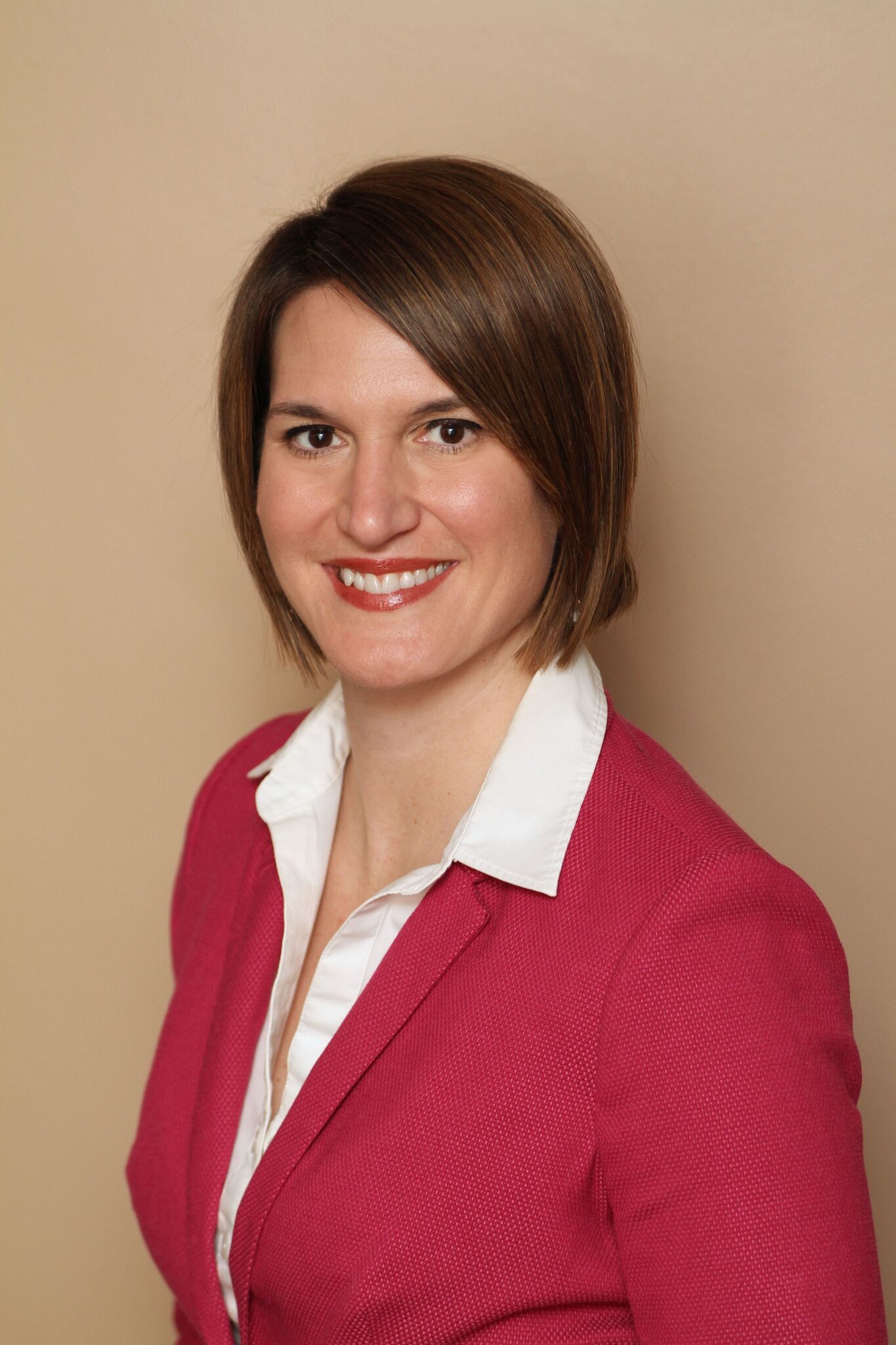 A woman in a pink blazer and white blouse smiles warmly, representing medbridge's healthcare education.