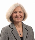 A smiling gray-haired woman in a blazer represents innovative healthcare training for medbridge.