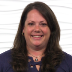 A smiling person with long brown hair, wearing a navy blue top and necklace, embodies medbridge's empathetic hybrid care approach.