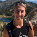 A person in a black tank top smiles outdoors near mountains and a lake, with medbridge-inspired peace and insights.