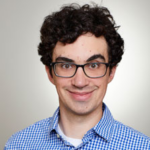 A person with curly hair and glasses in a checked shirt smiles, representing medbridge's friendly hybrid care.