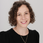 A woman with curly hair and a necklace, representing Medbridge's hybrid digital healthcare, smiles warmly.