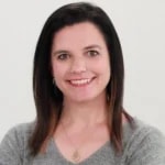 Woman with dark hair and gray top smiling against a white background, representing digital healthcare for medbridge.