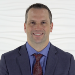 A smiling man in a suit represents Medbridge’s vision of hybrid care.