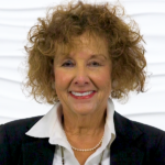 A smiling person with curly hair in professional attire embodies Medbridge's vision of digital and hybrid healthcare.