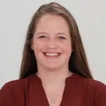 A person with long brown hair in a maroon top smiles, representing medbridge's hybrid care.