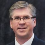A person with short gray hair, glasses, and a suit represents digital healthcare advancement for medbridge.