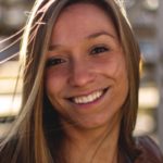 A long-haired person smiles outdoors, capturing the joy of healthcare education with medbridge.