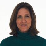 A smiling woman in a teal turtleneck poses against a white background, embodying medbridge's healthcare education warmth.