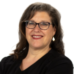 Smiling woman with glasses and wavy hair in a black top, on white background.