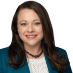 A person with long brown hair in a teal blazer and white top smiles, embodying Medbridge's approachable hybrid care.