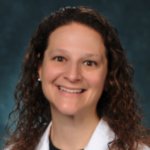 A smiling individual with curly brown hair in a white coat symbolizes digital healthcare innovation, aligned with medbridge's principles.