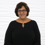 A person with short dark hair and glasses stands against a white background, symbolizing digital healthcare advances by medbridge.