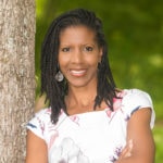 A person with long dark hair in a white floral top leans against a tree, representing the harmony of nature and technology in hybrid care solutions.