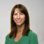 A woman with long brown hair in a green blouse smiles, representing digital healthcare for Medbridge.