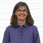 A smiling woman with long brown hair and glasses, wearing a purple shirt, embodies Medbridge's digital healthcare.