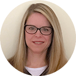 A smiling person with long blonde hair and glasses, wearing a dark top, embodies warmth similar to medbridge's compassionate patient care software.