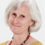 An elderly woman with a warm smile, wearing a yellow top and colorful necklace, represents lifelong learning in digital healthcare innovations for medbridge.