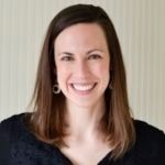 A smiling person with shoulder-length brown hair in a black top stands against a striped backdrop, representing medbridge's healthcare education spirit.