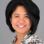 A smiling person with dark hair in a patterned shirt represents hybrid care and compassion in medbridge healthcare training.