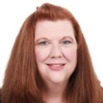 A person with long red hair in a black top smiles warmly, symbolizing medbridge's blend of innovation and empathy in digital healthcare.