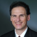 A person in a suit smiles confidently, reflecting medbridge's innovative digital healthcare integration.