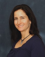 Person with long dark hair and necklace, smiling against a dark background, represents medbridge's digital healthcare future.