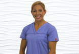 A person in a purple scrub top smiles against a white background, representing healthcare education for medbridge.