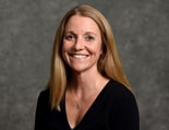 A smiling woman with long blonde hair, wearing a black top and necklace, represents modern digital healthcare for medbridge.