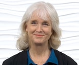 A smiling woman with white hair, in a black jacket and blue shirt, represents digital innovation at medbridge.