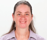 A smiling person with long hair in a light purple collared shirt is shown against a plain background.
