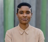 A person with short hair in a beige collared shirt stands before a colorful background, representing the future of digital healthcare and medbridge training.