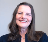 A smiling woman with long brown hair, wearing a cross necklace and a dark jacket, symbolizes compassionate healthcare training for medbridge.