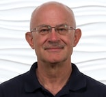 A bald man with glasses and a mustache stands confidently in a dark polo shirt, representing expertise at medbridge.
