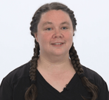 Individual with braided hair and a black shirt smiles against a white background.