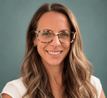 Smiling woman with long brown hair and tortoiseshell glasses in a white top, in front of a green background, representing medbridge.