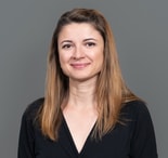 A smiling woman poses against a grey background, representing Medbridge digital healthcare training.