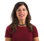 A woman smiles against a white background, promoting medbridge in a red shirt and necklace.