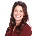 A smiling woman with long brown hair in a burgundy blouse represents Medbridge's digital healthcare innovation.