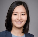 Woman with straight black hair in a blue blazer smiles at the camera, representing professionalism at medbridge.