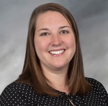 A woman with straight brown hair and a black polka dot blouse smiles, representing medbridge healthcare education.